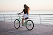 © Марина - Beautiful longhaired young woman with a bicycle having fun, cycling, posing on the camera near the sea on the sunrise