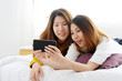 © mangpor2004 - Young cute asia lesbian couple using smart phone with happiness at home, lgbt, homosexual, lesbian couple lifestyle