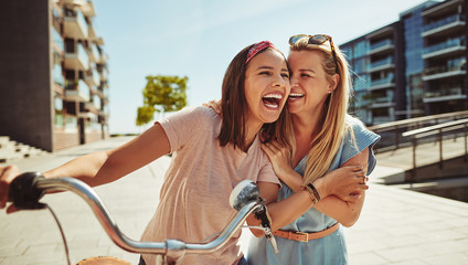 laughing female friends having fun walking together through the