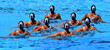 Synchronized swimming team performing a synchronized routine of elaborate moves in the water.
