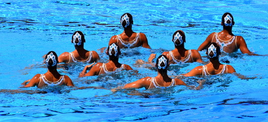 Synchronized swimming team performing a synchronized routine of elaborate moves in the water.