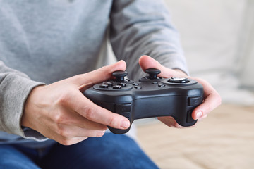 Poster - man holding a joystick controllers while playing a video games at home