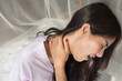 © 9nong - woman with shoulder or neck pain; portrait of asian woman suffering from stiff shoulder, neck bone dislocation, upper spinal injury or pain; body and health care concept; asian young adult woman model