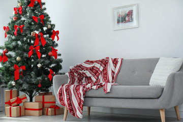 Stylish living room interior with decorated Christmas tree and comfortable sofa