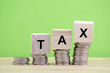 © amirul syaidi - TAX word written on wooden block with stacked coins on green background