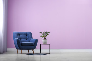 Poster - stylish comfortable armchair near color wall