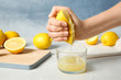 Woman squeezing lemon juice into glass on table