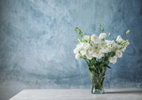 Vase with beautiful Eustoma flowers on table against color background