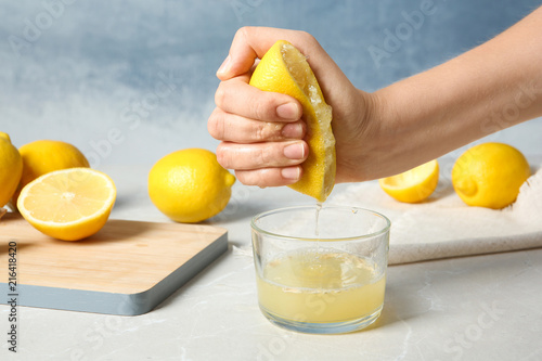 Fotografía Woman squeezing lemon juice into glass on table