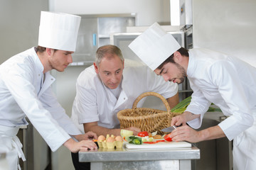 Poster - chief chef watching his assistants garnishing a dish