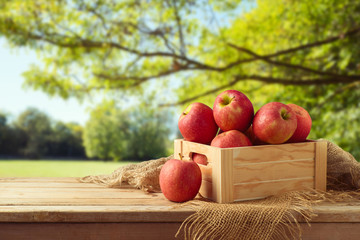 Red apples in wooden box on table