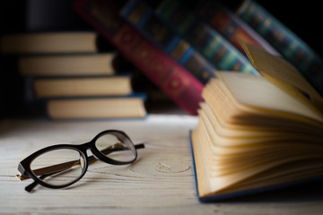 Glasses and book on library background