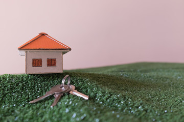 Model house and key on green artificial grass