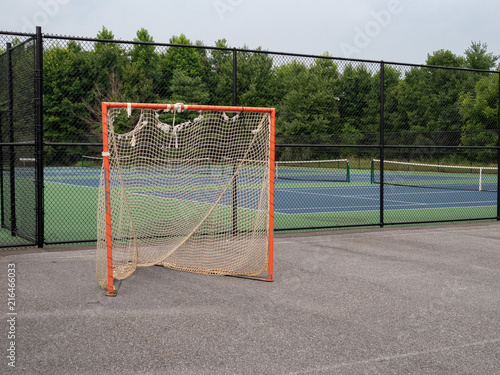 Fotografiet Offseason, beat up, rusted, ragged lacrosse goal sitting on asphalt court with n