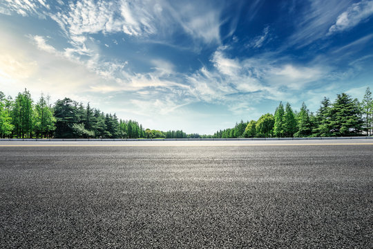 asphalt road and green forest landscape under the blue sky