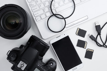 top view of camera, lenses, photography equipment, smart phone and computer over white
