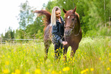 Fototapeta Konie - Happy woman feeding her arabian horse with snacks in the field