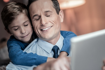 So pleased. Relaxed kid smiling while embracing his daddy