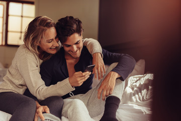 Wall Mural - Relaxed couple looking at mobile phone