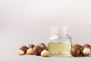 Wall Mural - Cosmetic macadamia oil and heap of nuts on table.