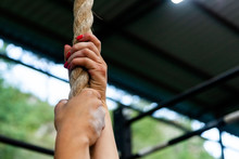 Close-up Young Woman Hanging On A Rope For Pull-ups, Hands In Magnesia Against The Backdrop Of A Gym