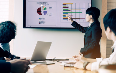 Asian business people holding pen pointing projector screen with group of employee during presentation.