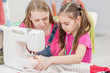 © Ermolaev Alexandr - Mother teaches a little girl to sew on a sewing machine