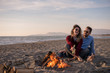 © .shock - Young Couple Sitting On The Beach beside Campfire drinking beer