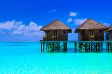 Water Villas On Wooden Pier In Turquoise Ocean On The White Sand Beach