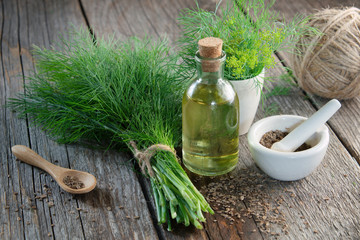 Wall Mural - Bunch of fresh green dill, mortar of fennel seeds and dill oil on wooden board.