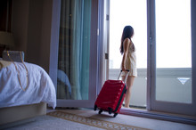 Lifestyle Portrait Of Young Happy And Beautiful Asian Korean Tourist Woman With Suitcase Arriving To Luxury Hotel Room Opening Balcony Windows