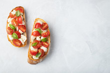 Bruschetta With Tomatoes, Mozzarella Cheese And Basil On A Light Background. Traditional Italian Appetizer Or Snack, Antipasto. Top View With Copy Space. Flat Lay