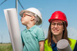 Cute little boy next to a positive mom with glasses and helmets on the background of blue skies. Concept of builders and architects
