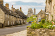 Corfe castle ruins in Dorset seen on a sunny summer day with traditional portland stone cottages lining the road in the foreground