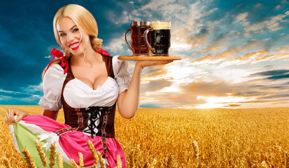 Wall Mural - Beer party. Sexy Oktoberfest woman - waitress, in Munich wearing a traditional german Bavarian dress, serving big beer mugs on golden wheat field background.