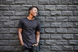 African american fashion male model in blank black t-shirt standing against brick wall