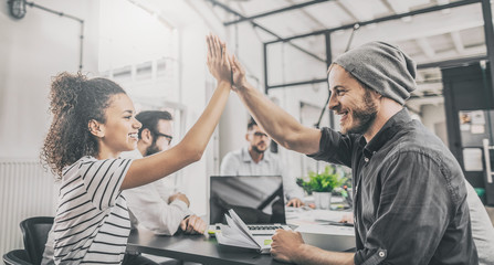Fototapete - Happy business people team giving high five in office.