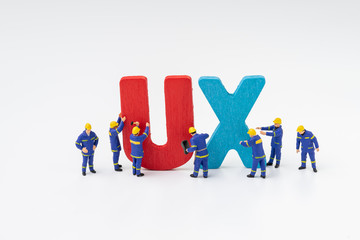 UX User Experience development and design concept, miniature people workers team building the colorful word UX with white background, user centric in modern world software, application and products