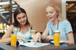 © fotofabrika - Two beautiful young girls sitting by the table in cafe