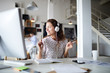 © pressmaster - Joyous young businesswoman with headphones listening to dynamic music while working by desk in front of computer monitor