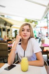 Wall Mural - Young beautiful woman sitting in a cafe drinking a cocktail