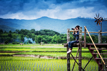 Tourist enjoy fresh air of countryside, on wooden bridge in rice field at north of Thailand