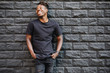 © antgor - Handsome african american man in black t-shirt laughing against brick wall