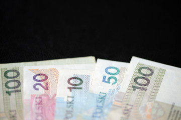 Several banknotes of Polish zloty on a dark background close up