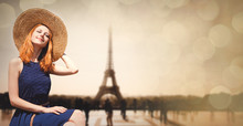 Young Girl In Dress And Hat Sitting At Street With Parisian Eiffel Tower On Background. Image With Bokeh And In Vintage Style