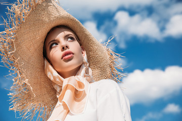fashionable attractive girl posing in trendy silk scarf and straw hat