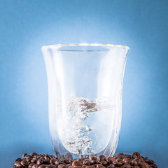 Transparent glass with water inside on blue background