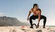 © Jacob Lund - Man doing fitness training at the beach with kettlebells