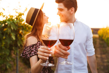 Poster - Happy loving couple outdoors drinking wine. Focus on glasses.