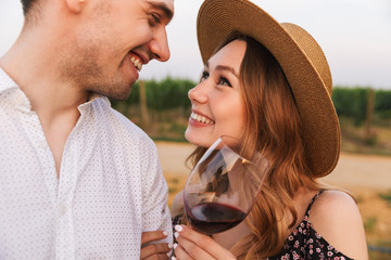 Poster - Loving couple outdoors holding glasses of wine.